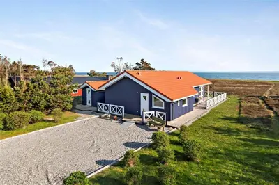 a blue house with an orange roof on the beach at LF308-Hurup-Thy-Edderfuglevej-10 in Sindrup