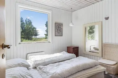 a white bedroom with a bed and a window at LF10236-Thyholm-Svinget-18 in Thyholm