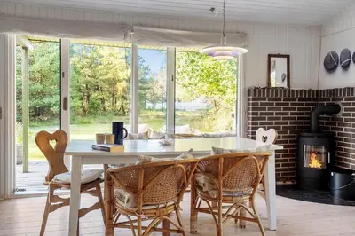a kitchen with a table and chairs and a fireplace at LF10236-Thyholm-Svinget-18 in Thyholm