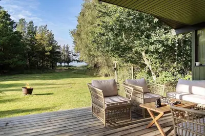 a patio with two chairs and a table on a deck at LF10236-Thyholm-Svinget-18 in Thyholm