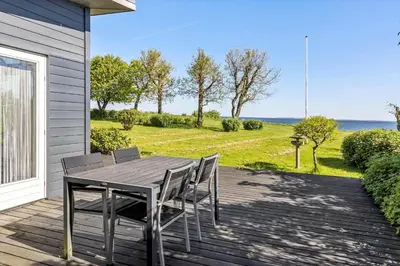 a table and chairs on a deck with a view of the ocean at LF14038-Roslev-Stranddalen-119 in Roslev