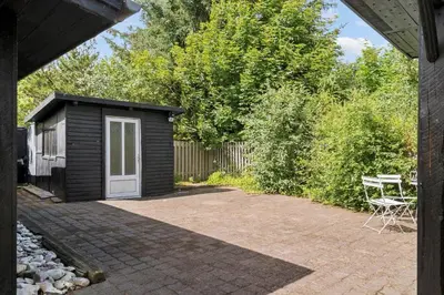 a small black shed with a white door and a table at LF10213-Thyholm-Haervej-9-B in Thyholm