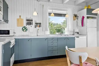 a kitchen with blue cabinets and a table at LF14127-Roslev-Kybehuse-127 in Roslev