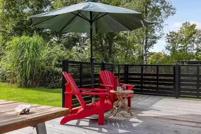two red chairs and a green umbrella on a deck at LF14223-Roslev-Livovej-9 in Roslev
