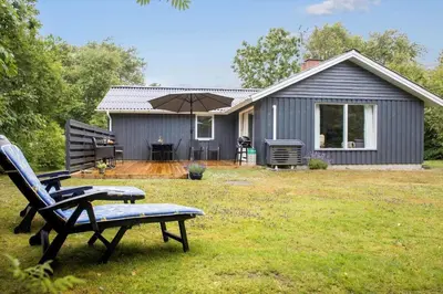 a house with a bench and an umbrella in a yard at LF10316-Hurup-Thy-Vagtelvej-16 in Sønder Ydby