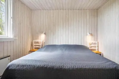 a bedroom with a bed in a room with two chairs at LF13172-Nykobing-M-Strandvaenget-76 in Ejerslev