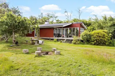 a red house with a picnic table in the yard at LF10221-Thyholm-Haervej-21 in Thyholm
