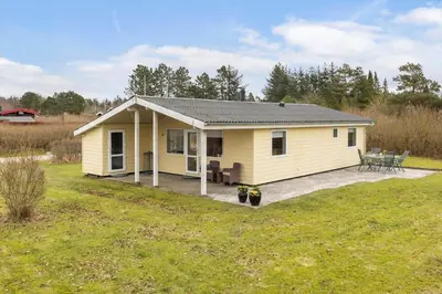 a small yellow house with a patio in a field at LF16021-Farso-Kjeldhoj-121 in Farsø