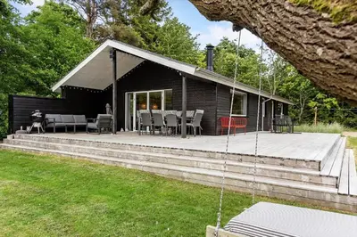 a log cabin with a deck with a table and chairs at LF14126-Roslev-Kybehuse-26 in Roslev