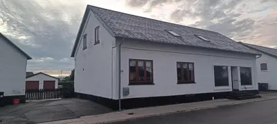 a white building with windows on the side of a street at Købmandsgården i Blære in Års