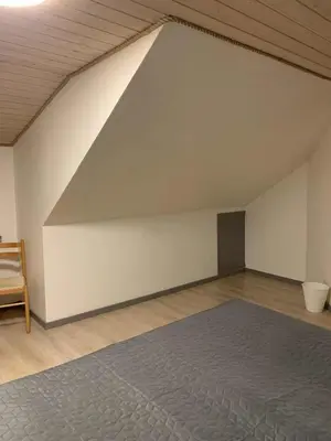 an attic room with a bed and a white wall at Købmandsgården i Blære in Års
