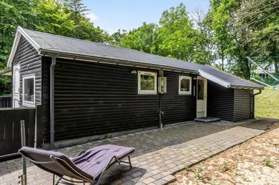 a black house with a chair in front of it at LF0027-Thyholm-Sondbjerg-Strandvej-27 in Thyholm