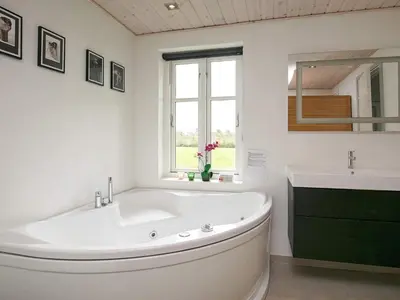 a white bathroom with a large tub and a sink at 10 person holiday home in Ranum in Ranum