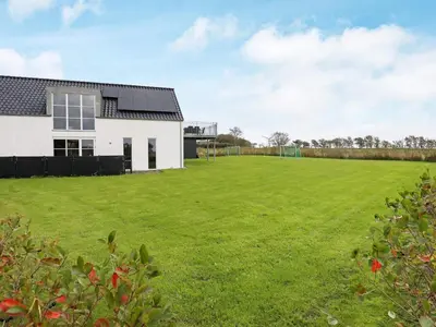 a large lawn in front of a white house at 10 person holiday home in Ranum in Ranum