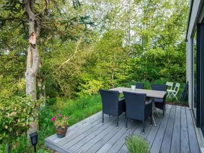 a wooden deck with a table and chairs on it at Tranquil Riverside Retreat in Holstebro