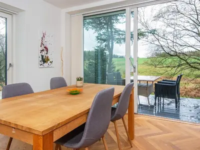 a dining room with a wooden table and chairs at Tranquil Riverside Retreat in Holstebro