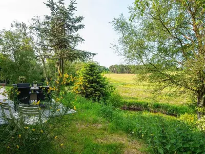 a garden with a pond and trees and a field at Tranquil Riverside Retreat in Holstebro