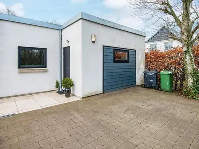 a white house with a blue garage door at Tranquil Riverside Retreat in Holstebro