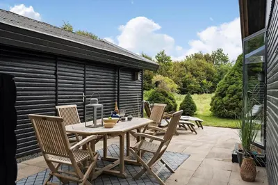 a wooden table and chairs on a patio at BL1116-Blokhus-Bloksbjerg-24 in Blokhus