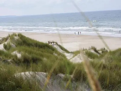 a beach with people on the sand and the ocean at 6 person holiday home in Blokhus