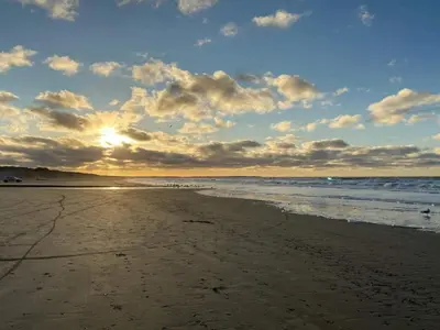 a sunset on a beach with the ocean at 6 person holiday home in Blokhus