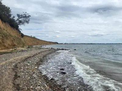 a beach with a rocky shore and the water at 6 person holiday home in Øster Assels in Øster Assels