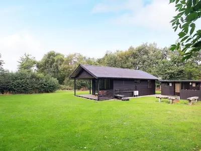 a cabin in a field with a grass yard at 6 person holiday home in Øster Assels in Øster Assels