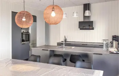 a kitchen with a counter with chairs and pendant lights at 3 Bedroom Nice Home In Løgstrup in Løgstrup