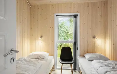 two beds in a room with a chair and a window at Nice Home In Fjerritslev With Sauna in Fjerritslev