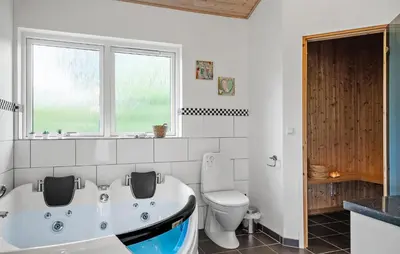 a bathroom with a tub and a toilet and a window at Nice Home In Fjerritslev With Sauna in Fjerritslev