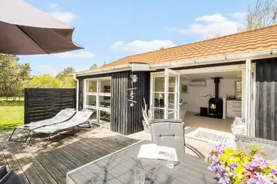 a patio with chairs and an umbrella on a deck at JB323-Fjerritslev-Markstien-21 in Fjerritslev