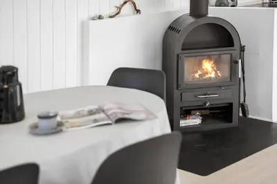 a fireplace in a room with a table with a book at JB323-Fjerritslev-Markstien-21 in Fjerritslev