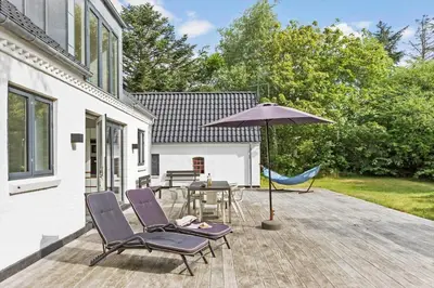 a patio with a table and chairs and an umbrella at JB1031-Fjerritslev-Thorup-Strandvej-266 in Fjerritslev