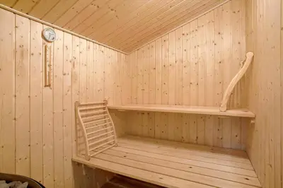 a wooden sauna with a chair and a clock at JB193-Fjerritslev-Blabaerstien-78 in Fjerritslev