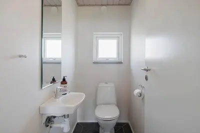 a bathroom with a toilet and a sink and a mirror at JB326-Brovst-Kronvildtvej-134 in Brovst