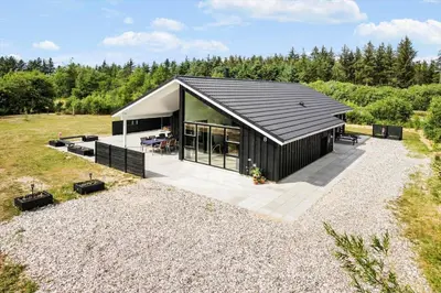 a house with a black roof on a gravel yard at JB208-Brovst-Kronvildtvej-8 in Brovst