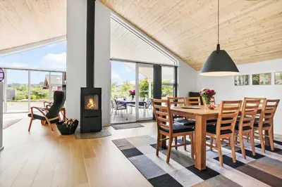a dining room with a table and a fireplace at JB208-Brovst-Kronvildtvej-8 in Brovst