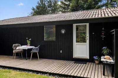 a black house with a wooden deck with a white door at JB922-Fjerritslev-Birkevej-25 in Fjerritslev