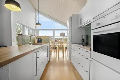a kitchen with white cabinets and a large window at JB225-Brovst-Kronvildtvej-218 in Brovst