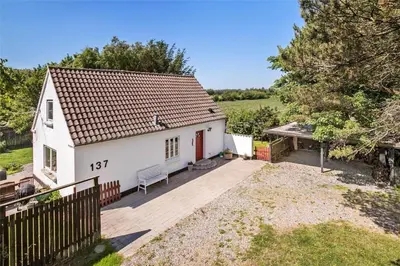 a small white house with a wooden deck at JB151-Brovst-Tranum-Engevej-137 in Brovst