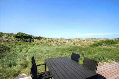 a wooden table and chairs on a deck with a view of the ocean at JB163-Brovst-Ejstrup-Strandvej-32 in Brovst