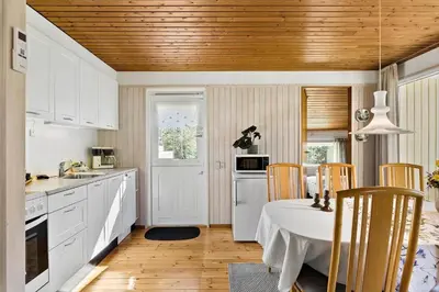 a kitchen with white cabinets and a table with chairs at JB157-Brovst-Krogen-24 in Brovst