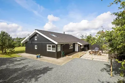 a black house with a garage in a yard at JB299-Brovst-Kronvildtvej-224 in Brovst