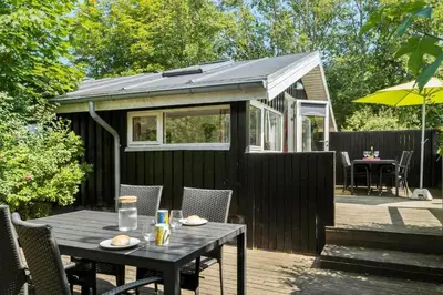 a black shed with a table and chairs on a deck at JB236-Fjerritslev-Ahornvej-22 in Fjerritslev
