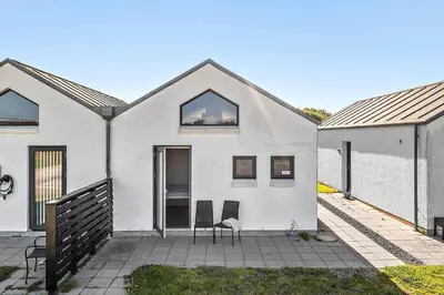 a white house with two windows and a chair at JB302-Fjerritslev-Slettestrandvej-134-lejl-6 in Fjerritslev