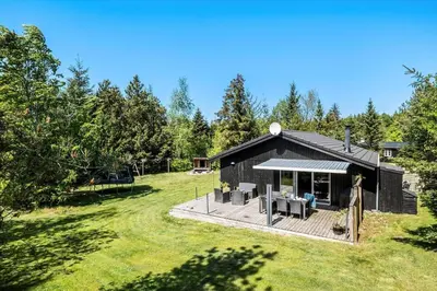 a black house with a deck in a yard at JB128-Fjerritslev-Pilevej-2 in Fjerritslev