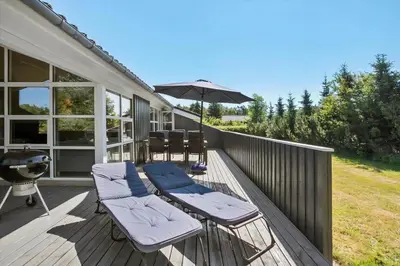 a deck with chairs and an umbrella and a grill at JB792-Fjerritslev-Egevej-34 in Fjerritslev