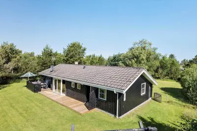 a black house with a deck on a yard at JB293-Fjerritslev-Tyttebaerstien-24 in Fjerritslev