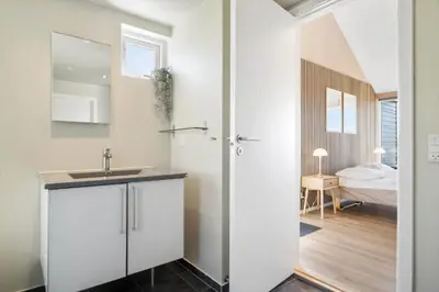 a white bathroom with a sink and a bedroom at JB214-Brovst-Kronvildtvej-214 in Brovst