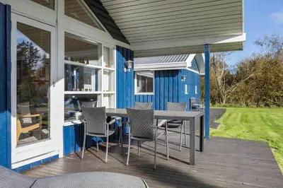 a blue house with a table and chairs on a deck at JB219-Fjerritslev-Tyttebaerstien-4 in Fjerritslev